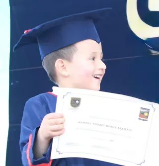 Niño del nivel inicial del Colegio Horizontes con birrete y diploma en su acto de promoción