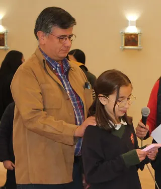 Un padre de familia acompaña a su hija, alumna del colegio, durante un acto en la capilla