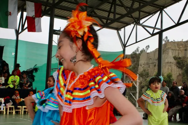 Alumnas del Colegio Horizontes bailan el Takirari con sombrillas de colores sobre el piso verde de la cancha techada, en el Día de la Familia por los 35 años del colegio.