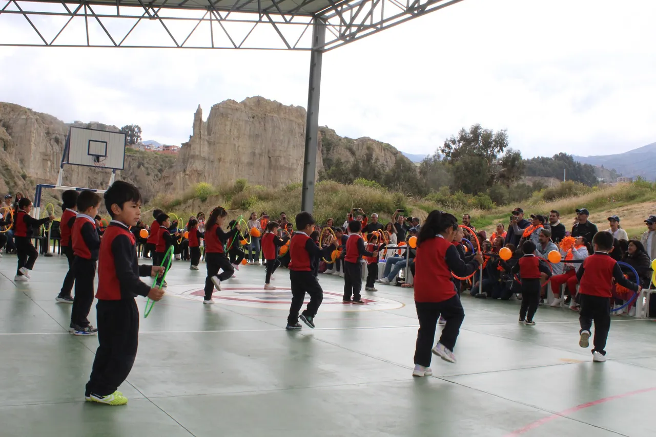Estudiantes de nivel inicial del Colegio Horizontes realizan un ejercicio con cintas de colores en la cancha techada, con las montañas de La Paz de fondo, durante el Día del Deporte.