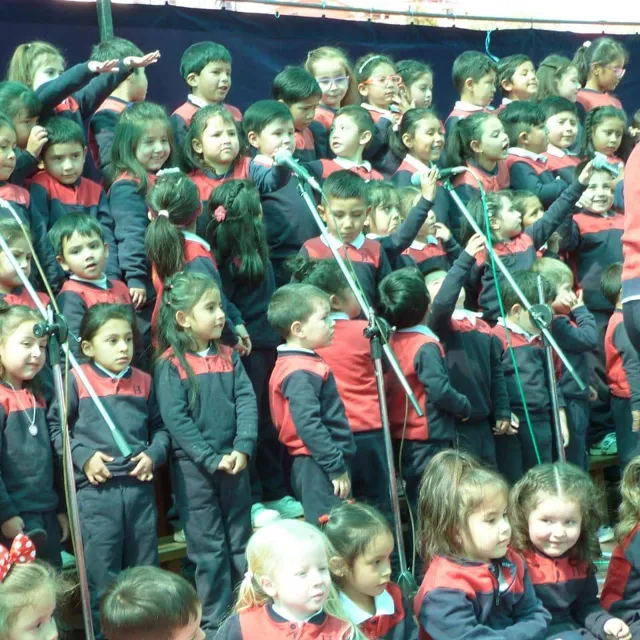 Un grupo numeroso de alumnas y alumnos del Colegio Horizontes canta frente a varios micrófonos durante un acto escolar.