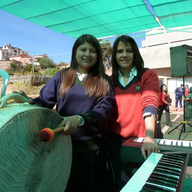 Una alumna del Colegio Horizontes toca un bombo junto a una profesora que toca el teclado, al aire libre.